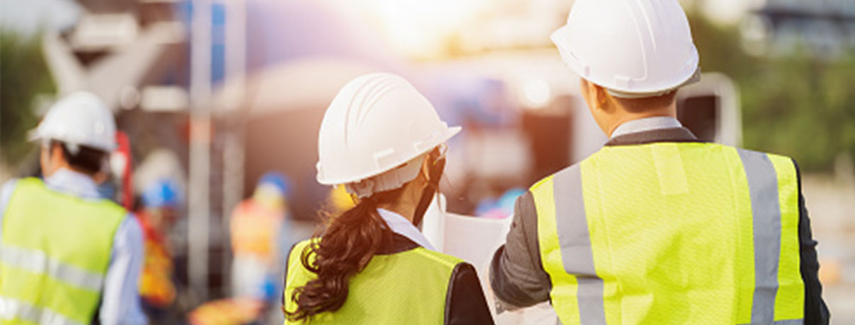 Businessman and businesswoman using see plan paper at construction site