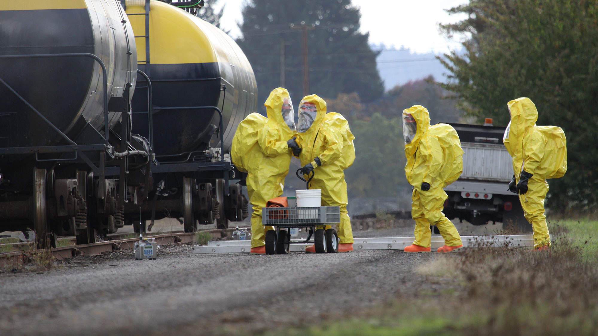 workers in safety suits next to train transporting oil