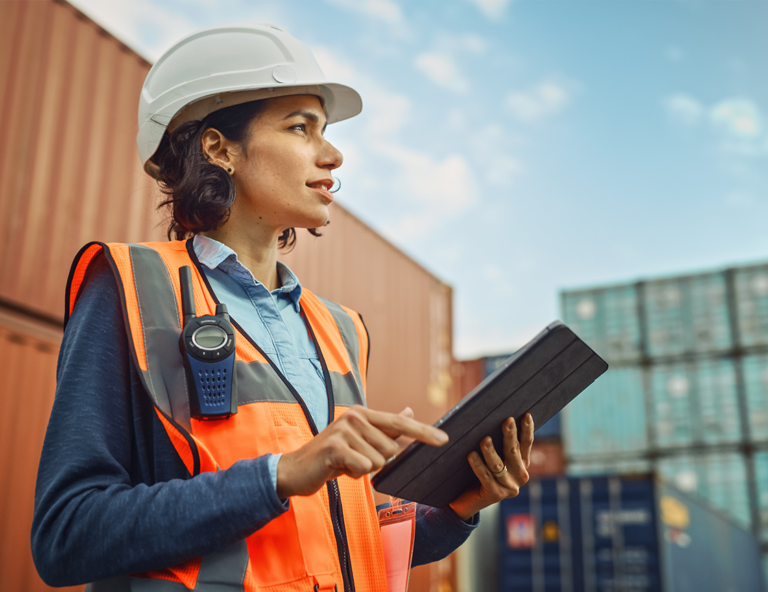woman-in-hardhat-and-vest-holding-tablet-in-shipping-yard