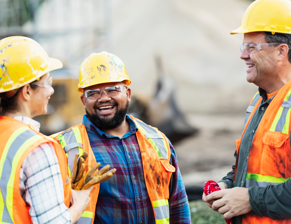 two-men-and-a-woman-laughing-wearing-hard-hats-and-safety-vests
