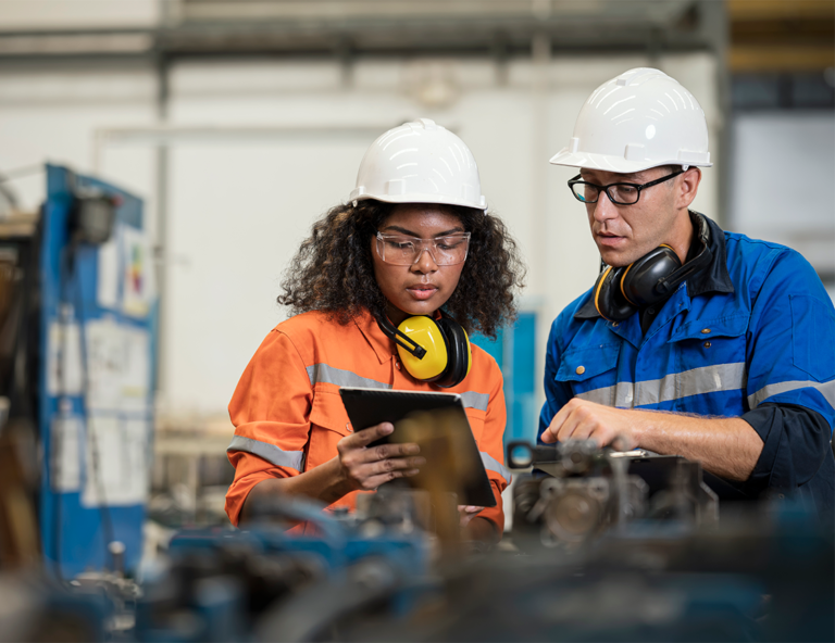 man-and-woman-with-hard-hats-in-factory-looking-at-ipad