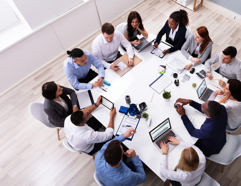 group-of-people-sitting-at-work-table-with-laptops-and-tablets