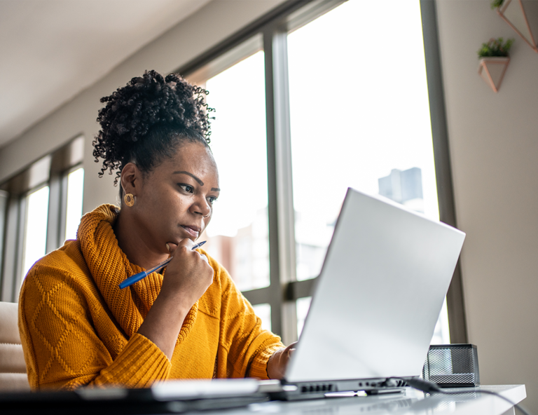 woman-looking-at-laptop-screen-with-hand-on-her-chin