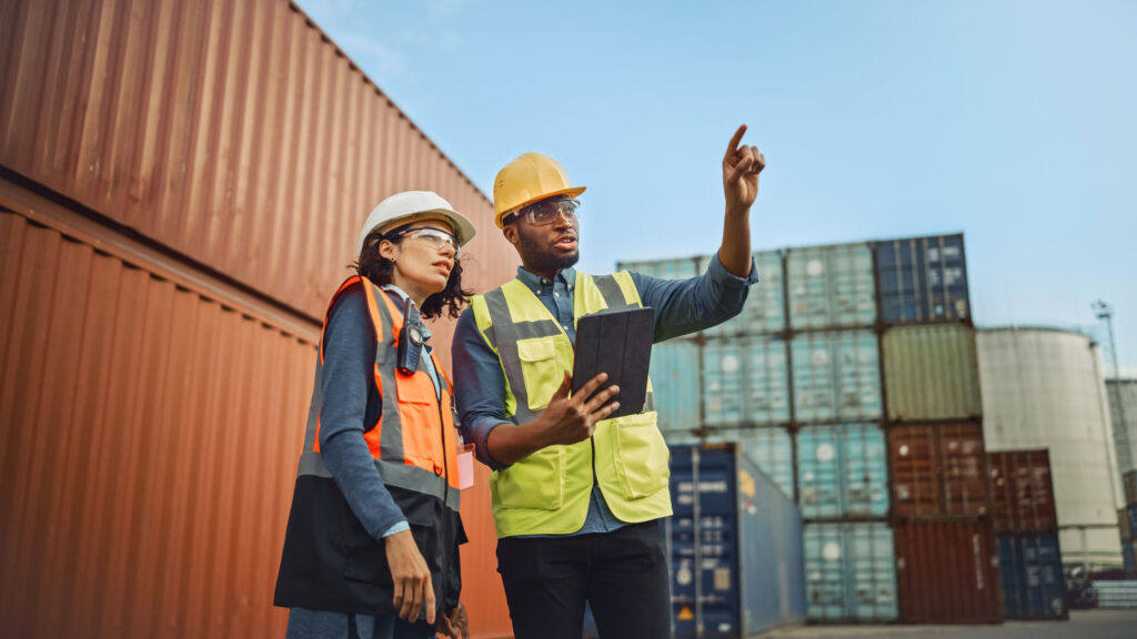 two-engineers-in-hard-hats-stand-in-a-container-terminal