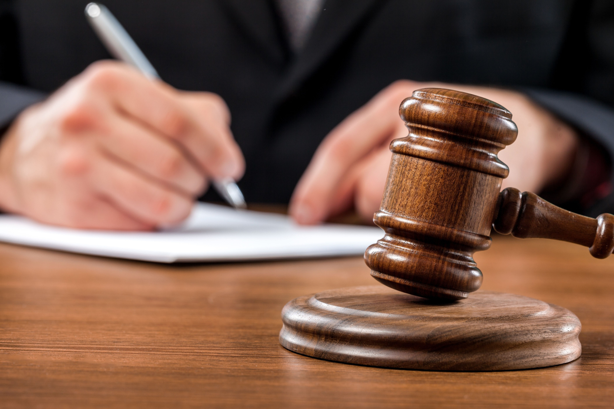 gavel with someone signing paper in background