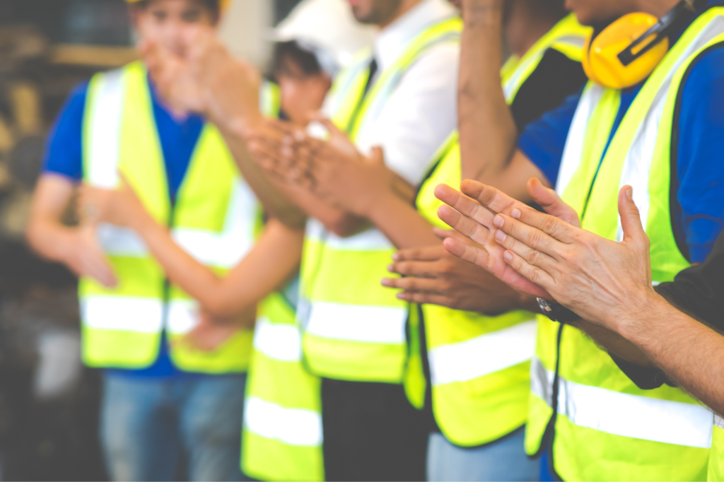 group of workers in safety vests clapping