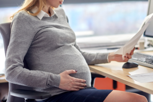 pregnant woman working at desk reviewing paper