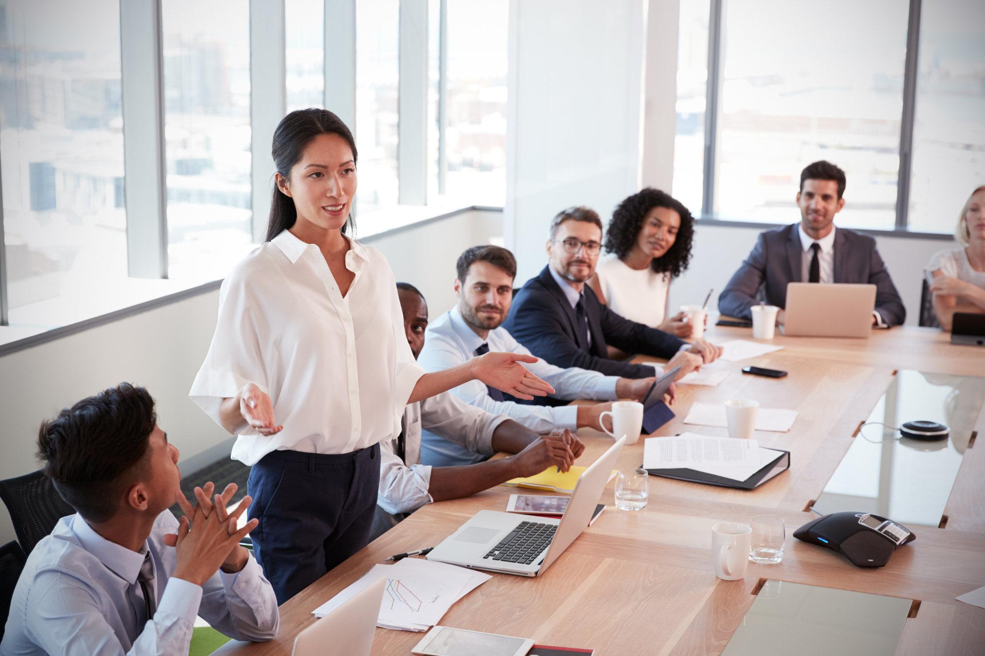 group of people working together, one woman standing to lead the group