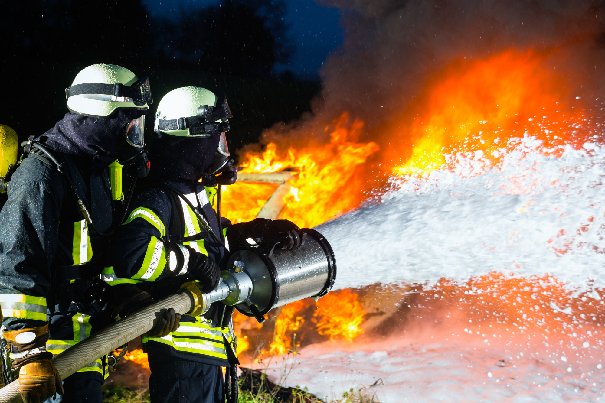 two firefighters using firefighting foam to extinguish a fire