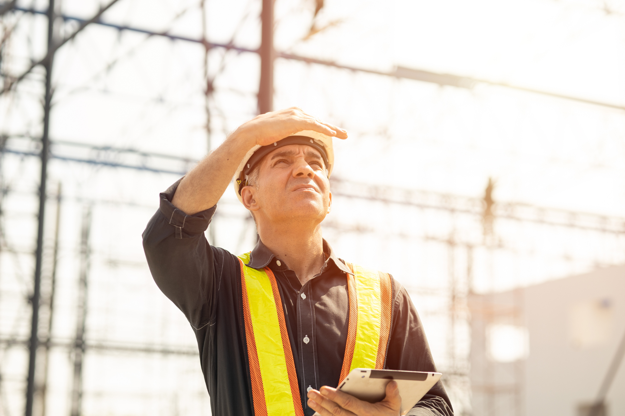 outdoor worker shielding his eyes from the sun with his hand