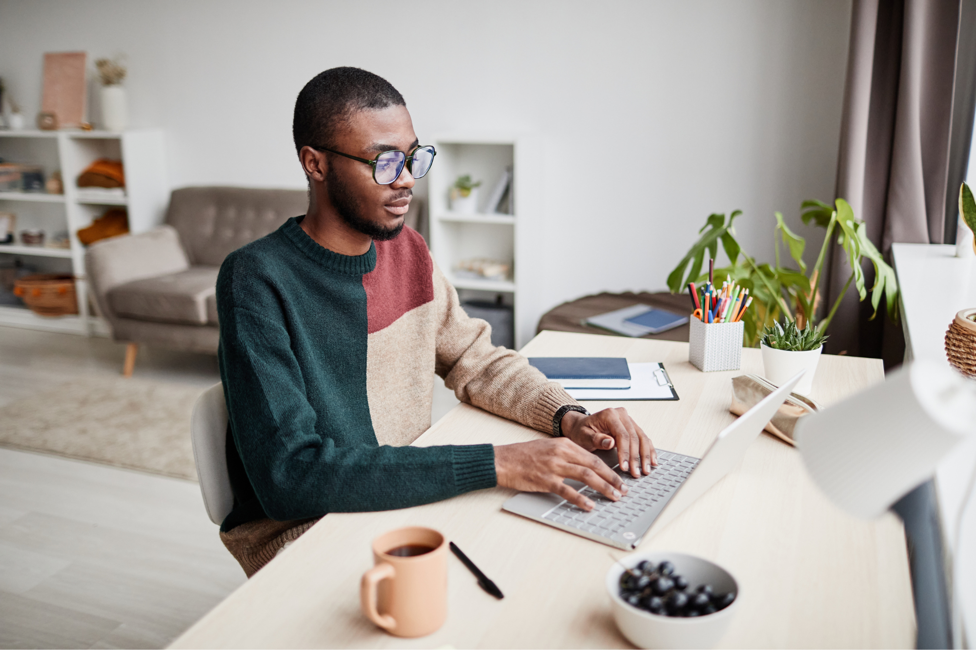 man with glasses working from home on laptop