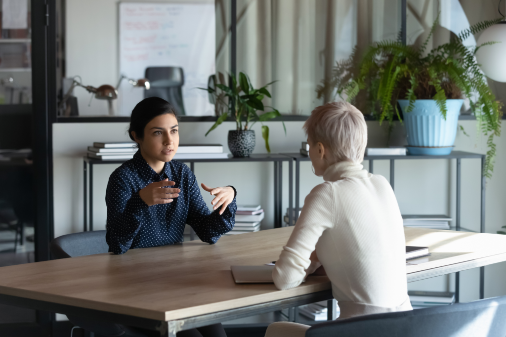 two women conversing at a desk