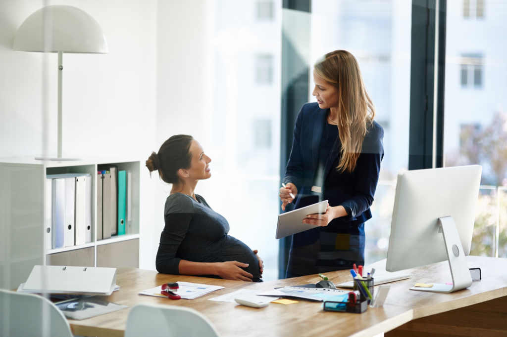 woman talking to a pregnant worker at her desk