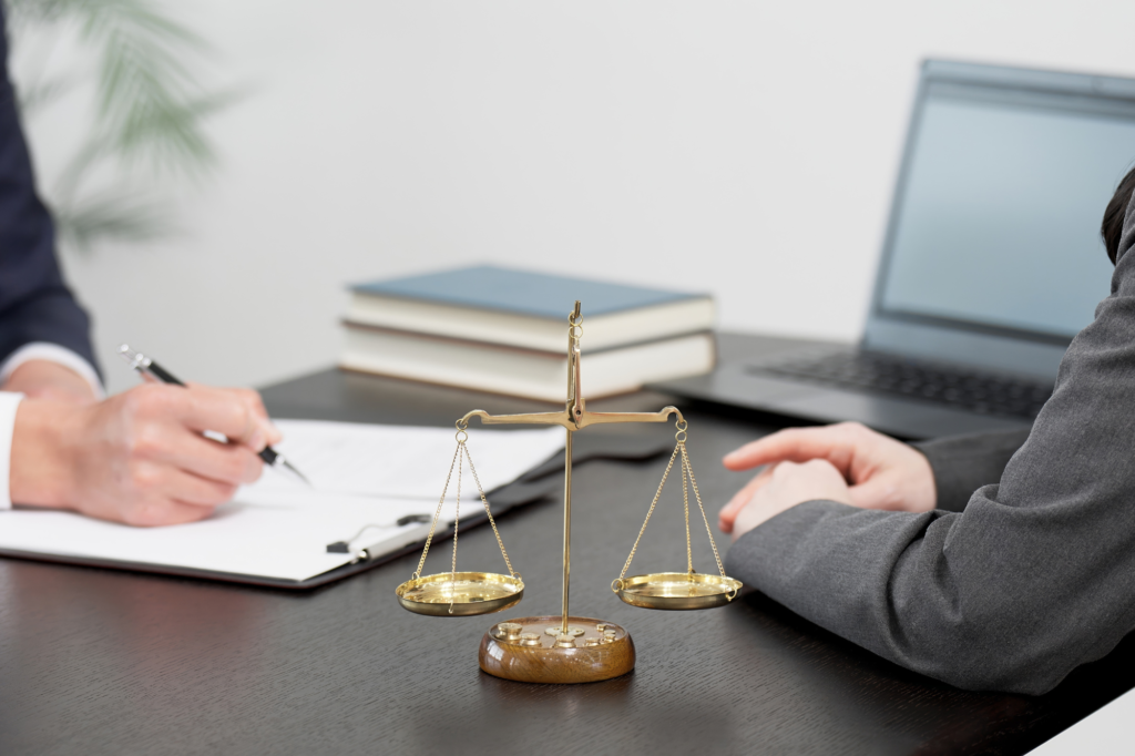 employer and employee sitting at a desk, reviewing documents with a scale in sight