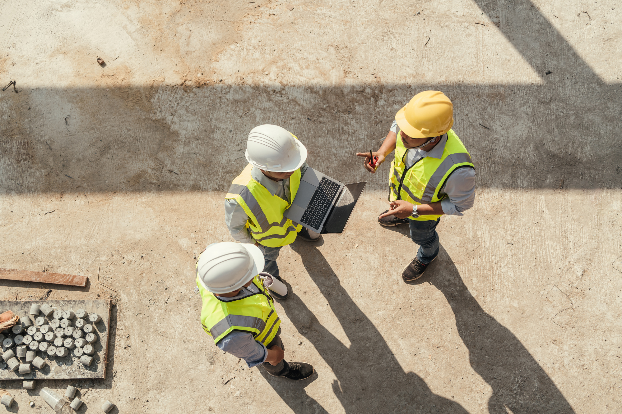 three people in safety gear having a discussion outside with computer