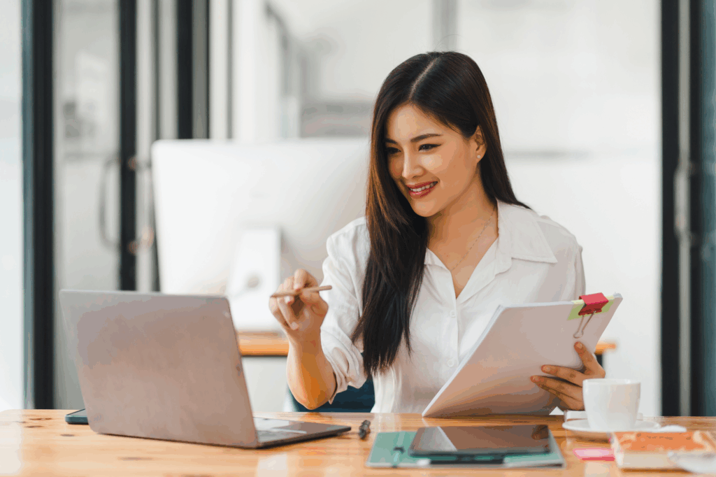 woman conducting an audit using a computer and evaluating paperwork