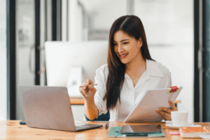 woman conducting an audit using a computer and evaluating paperwork