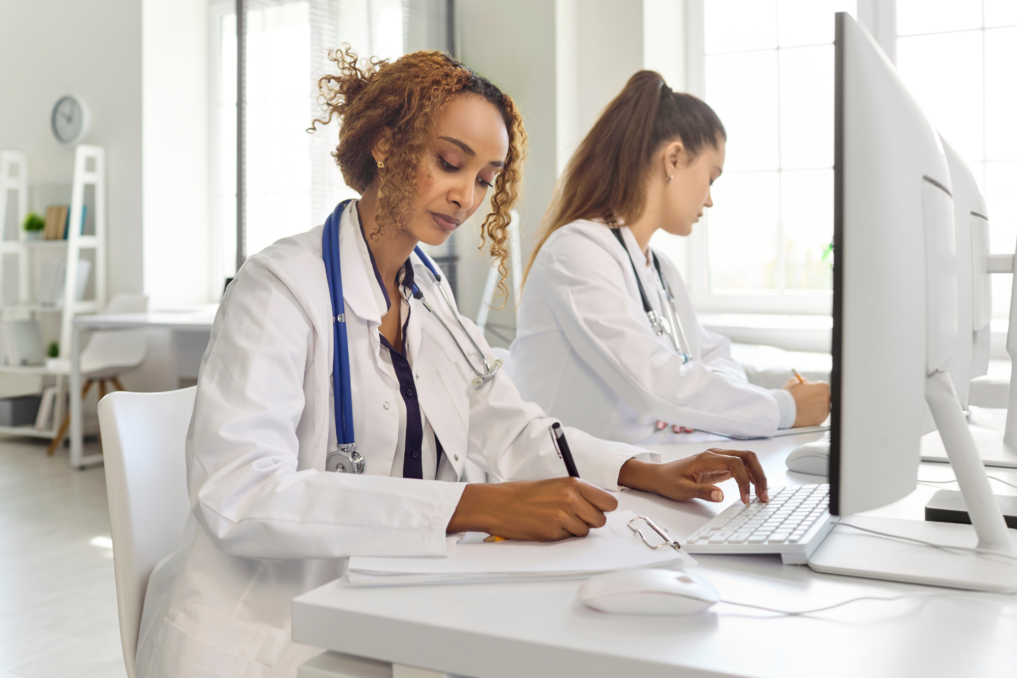 Healthcare professionals reviewing employee records and training documentation on computers in a medical office.