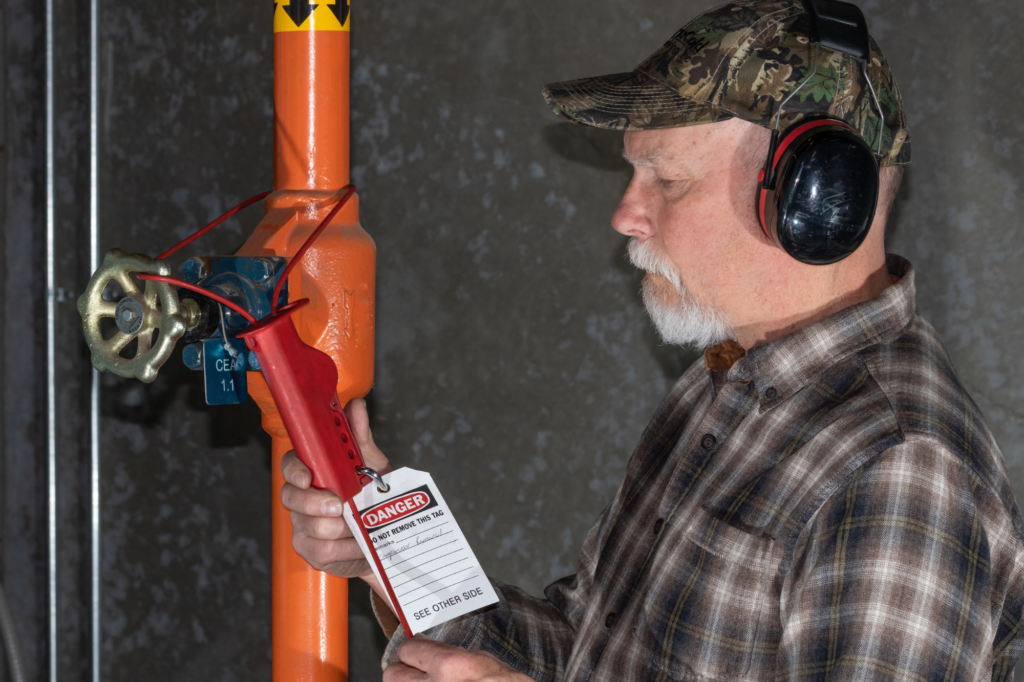 Worker applying a lockout/tagout device to an ammonia valve before maintenance to isolate hazardous energy.